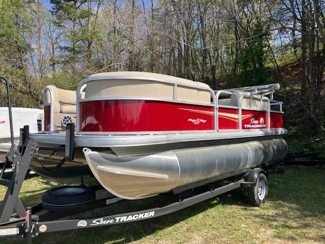 The Image of 2025 Sun Tracker Party Barge 18 DLX pontoon boat on trailer, parked outdoors. - 0