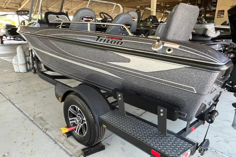 Slide: The Image of 2024 Triton 186 Allure boat interior with open storage compartments and steering wheel. - 5