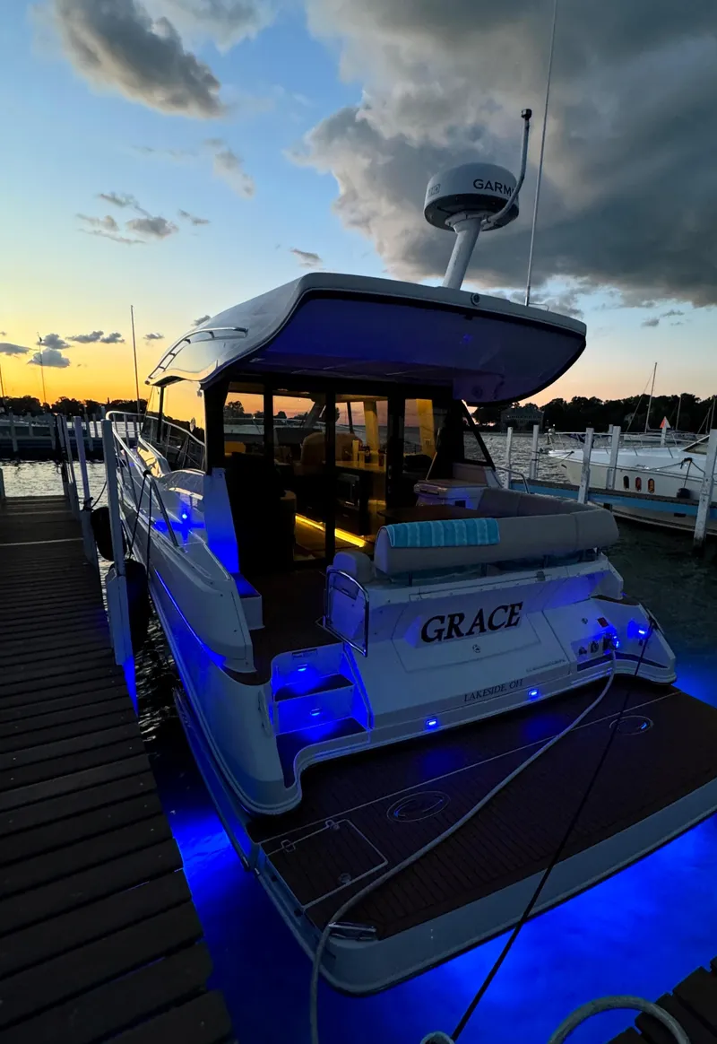 Slide: The Image of 2018 Regal 42 Grande Coupe yacht docked at sunset with blue underwater lights. - 1