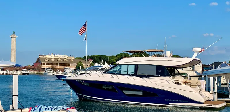 Slide: The Image of 2018 Regal 42 Grande Coupe yacht docked in a scenic marina with clear blue skies. - 2