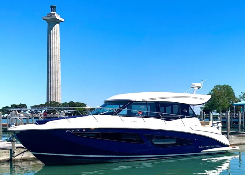 Slide: The Image of 2018 Regal 42 Grande Coupe yacht docked near a tall monument on a sunny day. - 3