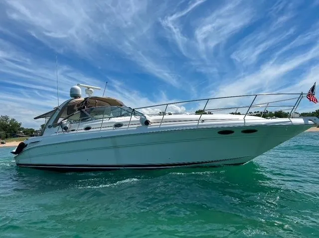 The Image of 2002 Sea Ray 410 Sundancer yacht cruising on clear blue water under a vibrant sky. - 0