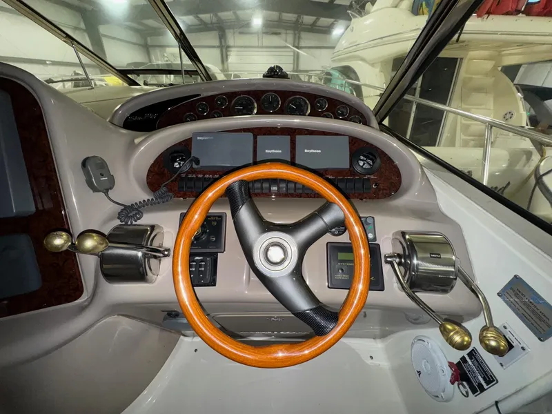 Slide: The Image of 2002 Sea Ray 410 Sundancer helm with wood-accented steering wheel and modern controls. - 17