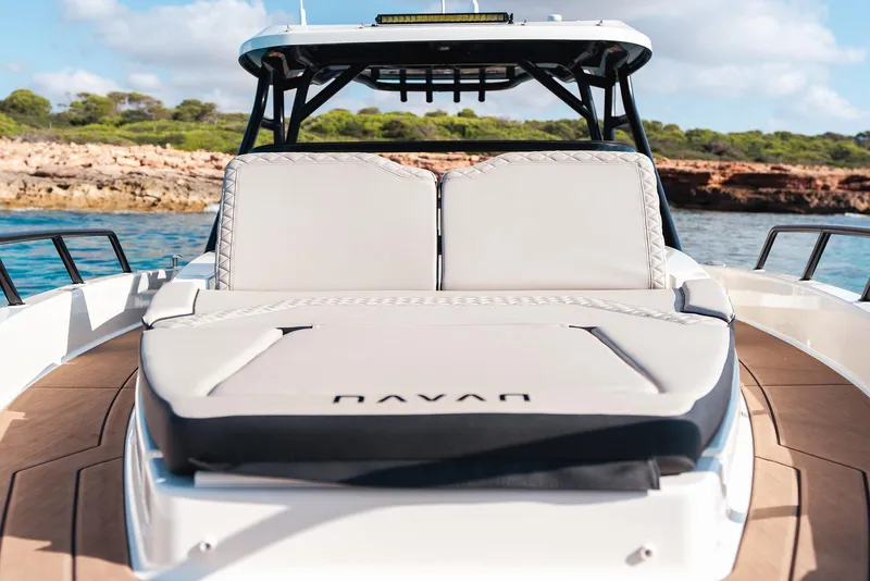 Slide: The Image of 2025 Navan S30 boat with cushioned seating, docked near a scenic coastline. - 2