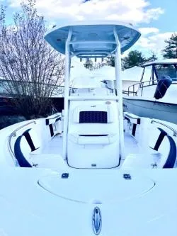Slide: The Image of 2025 Tidewater 198 CC Adventure boat with T-top, docked under a blue sky. - 3