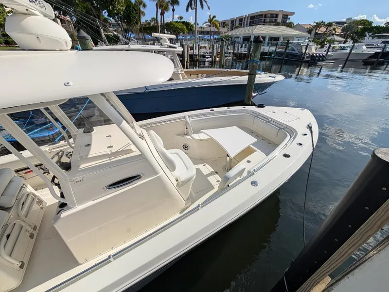Slide: The Image of 2023 Cobia 301 Center Console boat docked in a marina, showcasing sleek design and spacious deck. - 10
