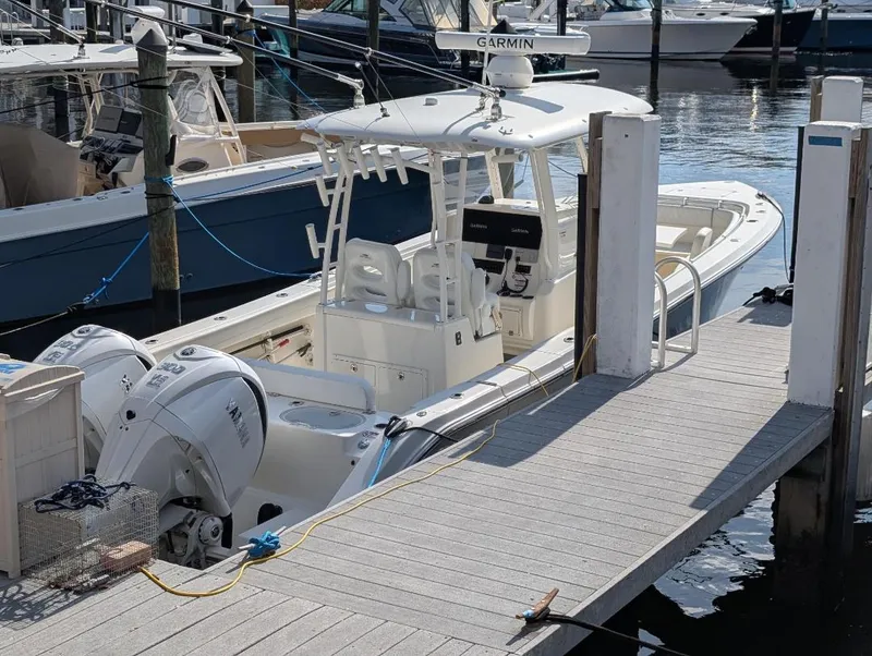 Slide: The Image of 2023 Cobia 301 Center Console boat docked at marina with twin engines. - 12