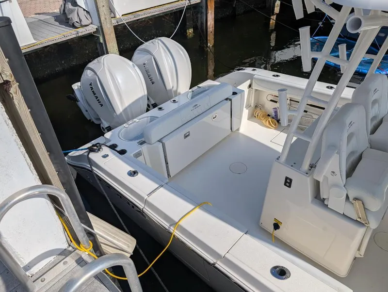 Slide: The Image of 2023 Cobia 301 Center Console boat docked with twin Yamaha engines. - 14