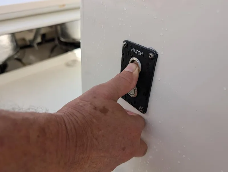 Slide: The Image of Hand pressing hatch button on 2023 Cobia 301 Center Console boat. - 28
