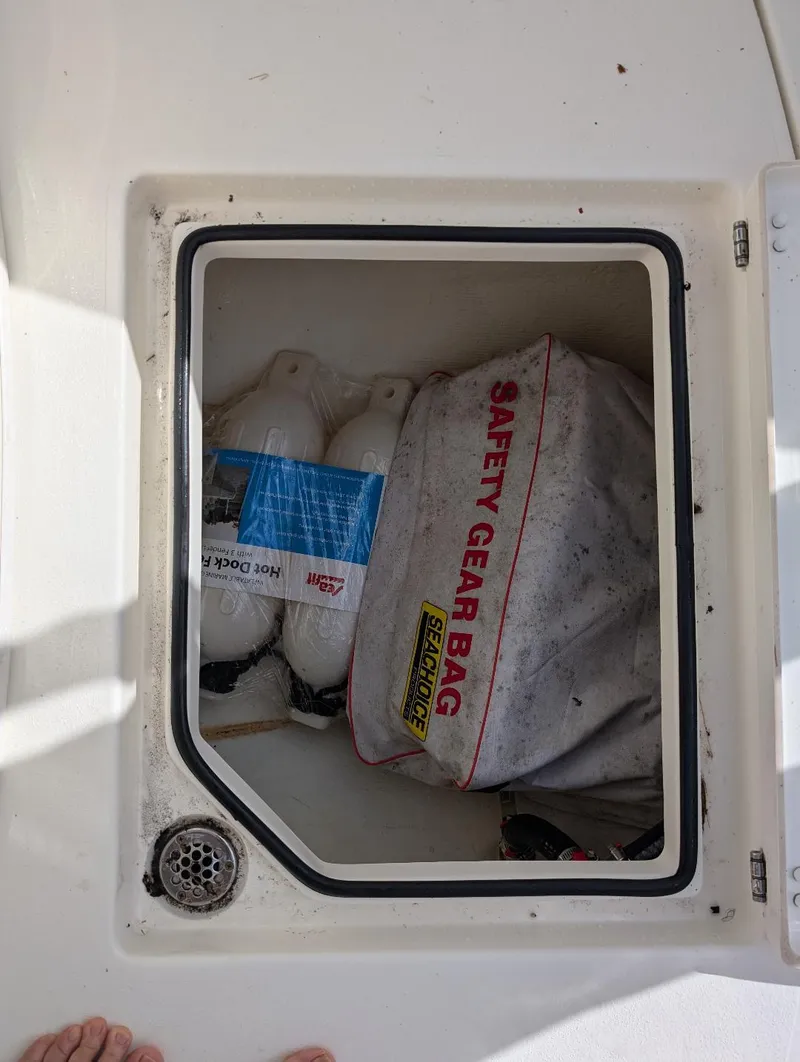 Slide: The Image of Storage compartment on 2023 Cobia 301 Center Console with safety gear and fenders. - 30