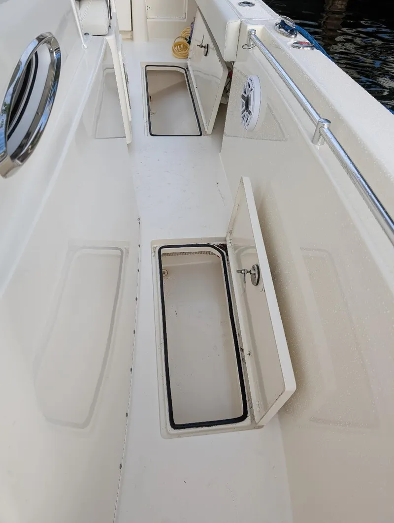 Slide: The Image of 2023 Cobia 301 Center Console boat deck with open storage compartments. - 33