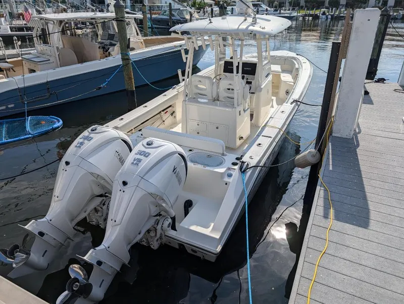 Slide: The Image of 2023 Cobia 301 Center Console boat docked with twin outboard engines. - 4