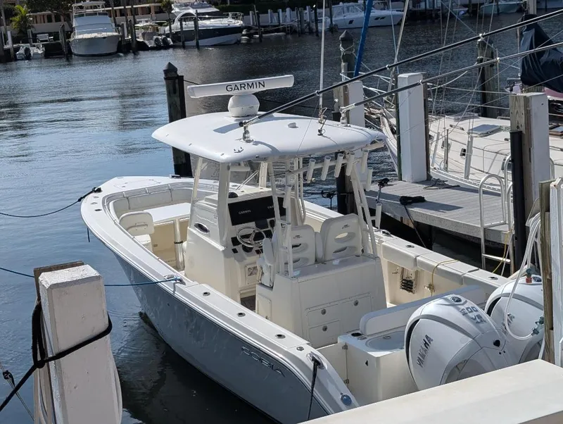 Slide: The Image of 2023 Cobia 301 Center Console boat docked at marina with twin engines. - 7