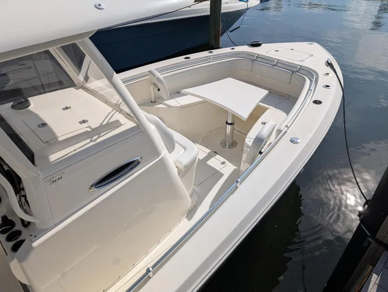 Slide: The Image of 2023 Cobia 301 Center Console boat docked, featuring spacious seating and a central table. - 9