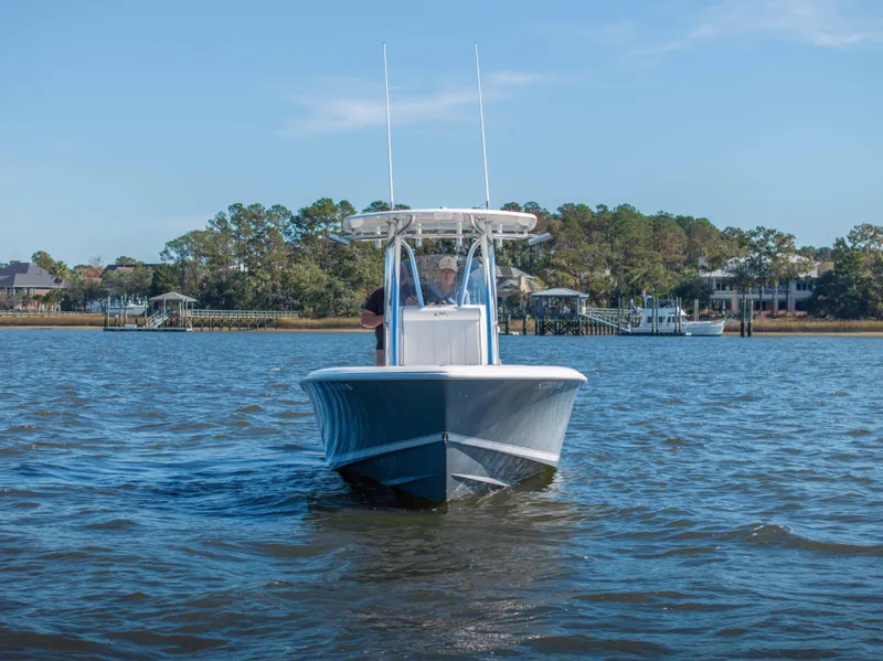 Slide: The Image of 2022 Contender 25 boat cruising on a calm lake with scenic background. - 16