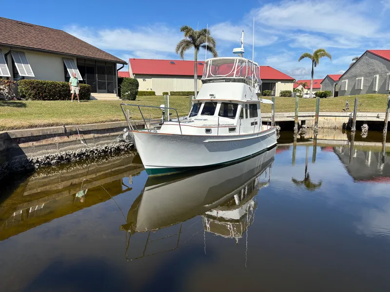 Slide: The Image of 2000 Legacy Flybridge Downeast boat docked in a calm marina with clear skies. - 1