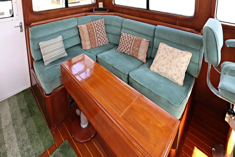 Slide: The Image of 2000 Legacy Flybridge Downeast interior with teal seating, wooden table, and decorative cushions. - 34