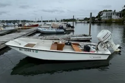 The Image of 1981 Boston Whaler 13 boat docked at marina, overcast sky, calm water. - 0