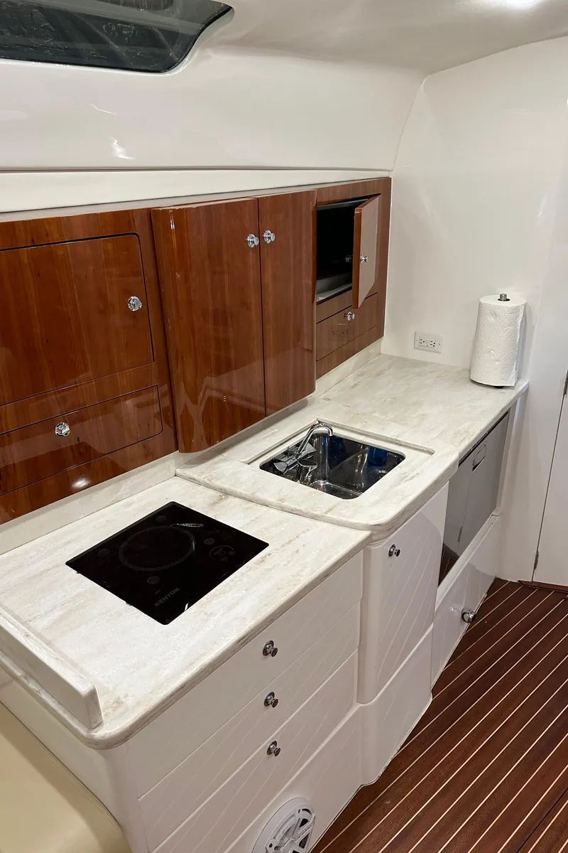 Slide: The Image of 2017 Intrepid 430 Sport Yacht kitchen with sleek cabinetry, stovetop, and sink. - 38