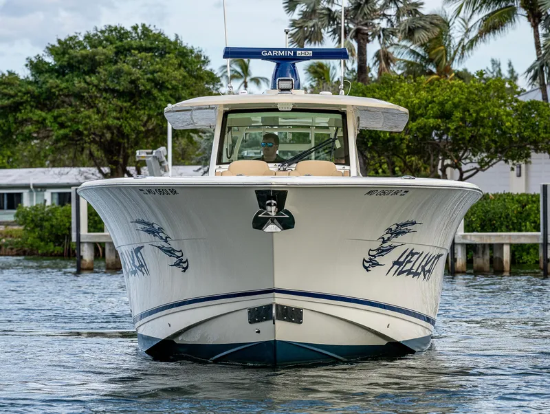 Slide: The Image of 2019 Scout 420 LXF boat on water, front view with trees in background. - 16