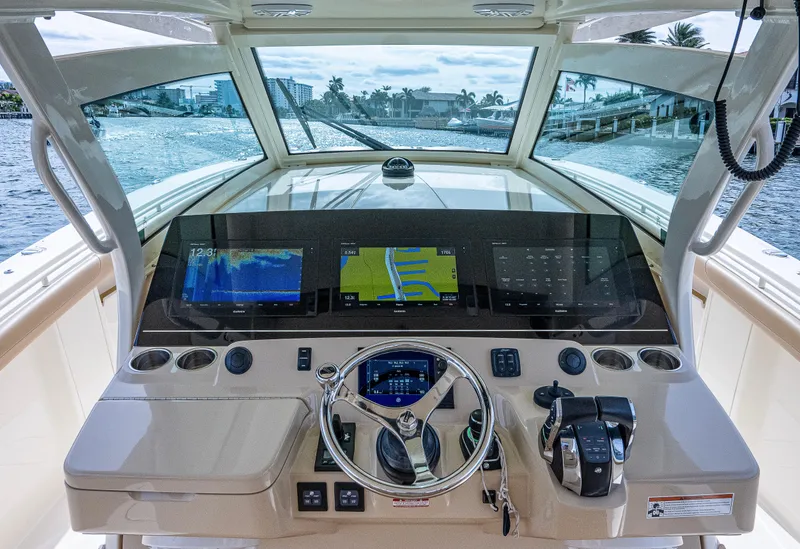 Slide: The Image of 2019 Scout 420 LXF boat dashboard with navigation screens and steering wheel. - 2