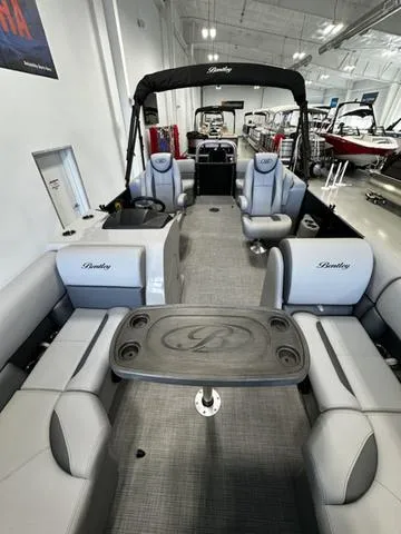 Slide: The Image of 2025 Bentley Pontoons 200 Navigator interior with gray seating and table in showroom. - 8