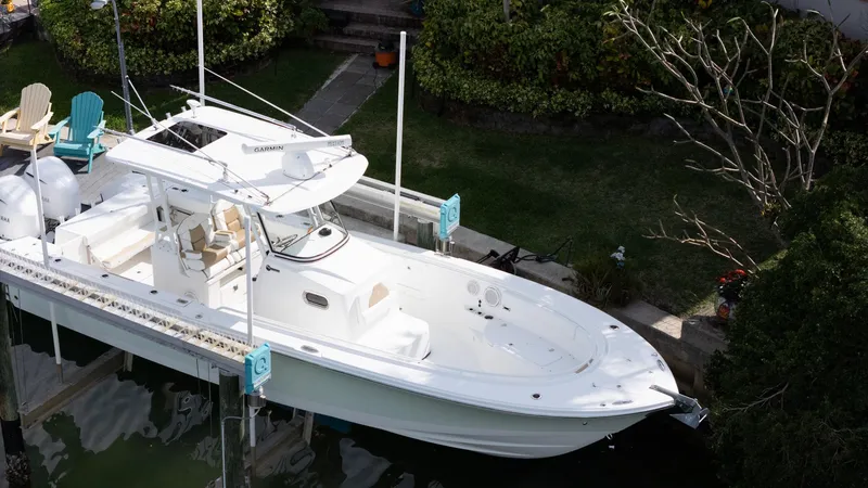 Slide: The Image of 2019 Edgewater 320CC boat docked in a lush, green marina setting. - 10