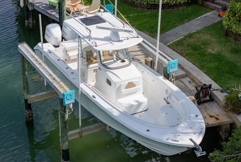 Slide: The Image of 2019 Edgewater 320CC boat docked in a serene waterfront setting. - 12