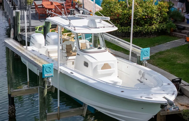 Slide: The Image of 2019 Edgewater 320CC boat docked, featuring dual engines and spacious deck. - 13