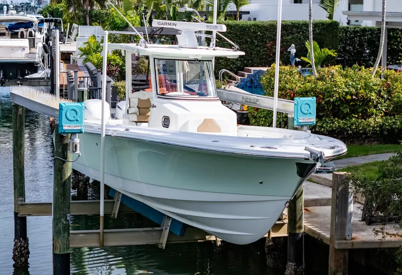 Slide: The Image of 2019 Edgewater 320CC boat docked on a lift in a marina setting. - 14
