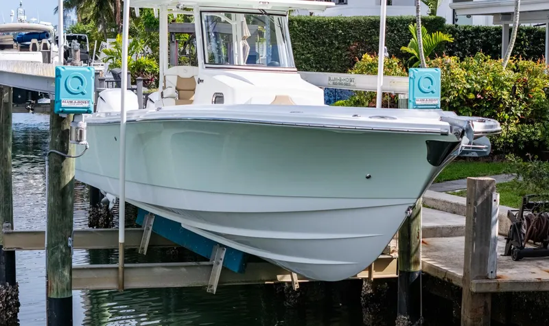 Slide: The Image of 2019 Edgewater 320CC boat docked on lift, surrounded by lush greenery. - 16