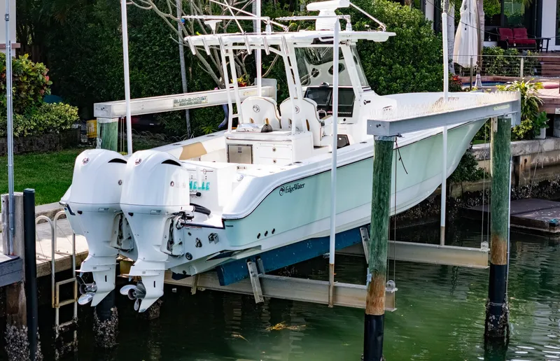 Slide: The Image of 2019 Edgewater 320CC boat on lift, dual engines, docked by waterfront property. - 17