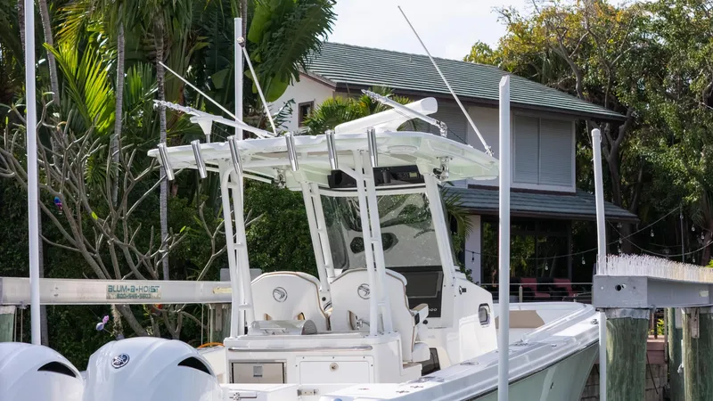 Slide: The Image of 2019 Edgewater 320CC boat docked near a house with lush greenery. - 21