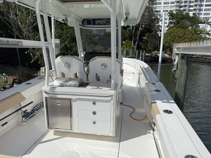Slide: The Image of Edgewater 320CC 2019 boat interior with seating and storage, docked near water. - 27