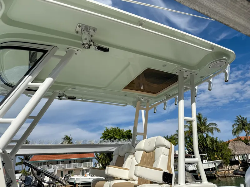 Slide: The Image of 2019 Edgewater 320CC boat with seating and canopy, docked under a clear blue sky. - 36