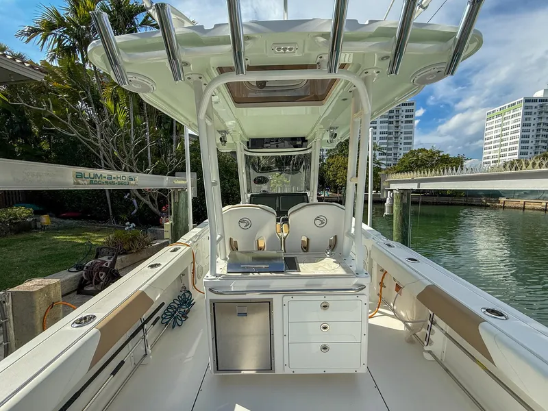 Slide: The Image of 2019 Edgewater 320CC boat interior with seating and storage, docked near waterfront buildings. - 37
