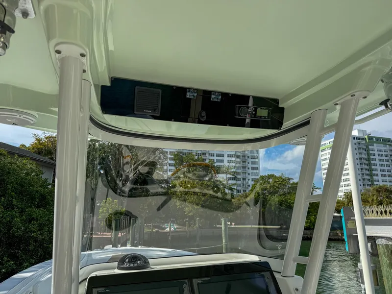 Slide: The Image of 2019 Edgewater 320CC boat console with overhead electronics, docked near waterfront buildings. - 42
