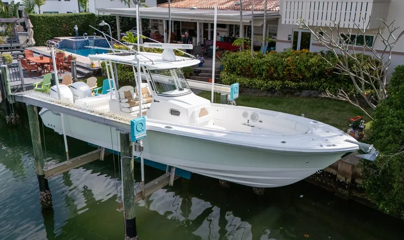 Slide: The Image of 2019 Edgewater 320CC boat docked near a waterfront home. - 7