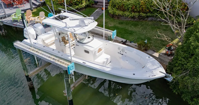 Slide: The Image of 2019 Edgewater 320CC boat docked on a lift, surrounded by greenery. - 9