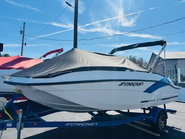 Slide: The Image of 2024 Starcraft SVX 171 boat on trailer, covered, outdoors under blue sky. - 3