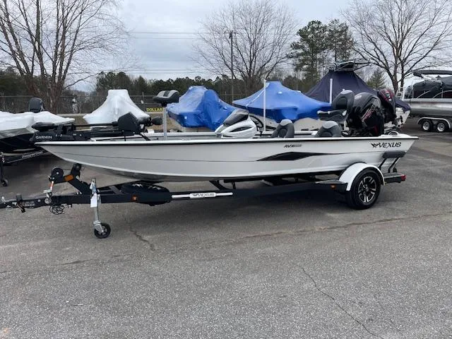Slide: The Image of 2025 Vexus AVX V2 1880 boat on trailer, parked outdoors, surrounded by other covered boats. - 3