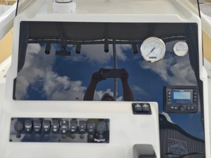 Slide: The Image of 2025 Savannah 2200 Offshore dashboard with gauges and controls, reflecting sky and person. - 11