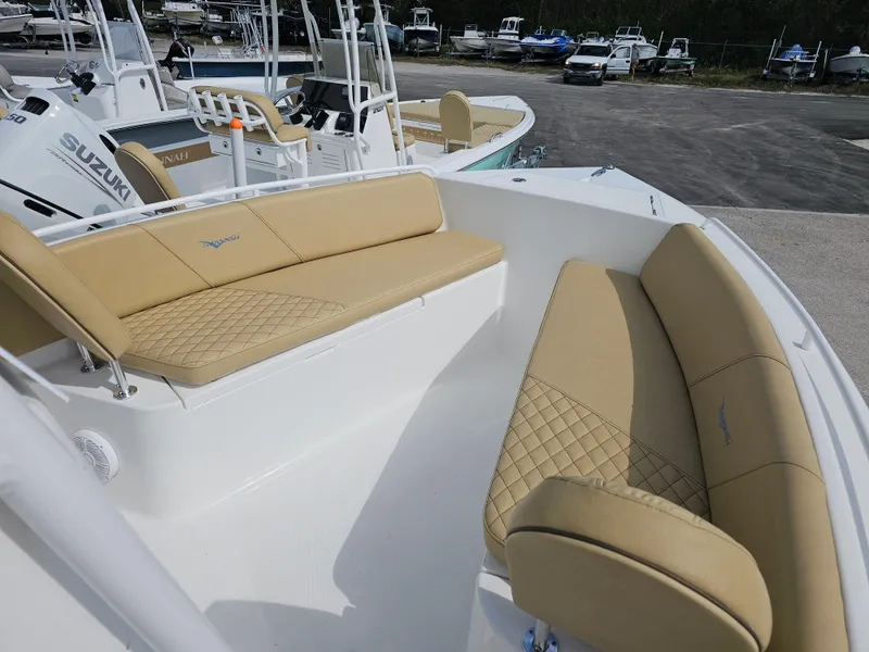 Slide: The Image of 2025 Savannah 2200 Offshore boat with tan cushioned seating, docked with other boats. - 3