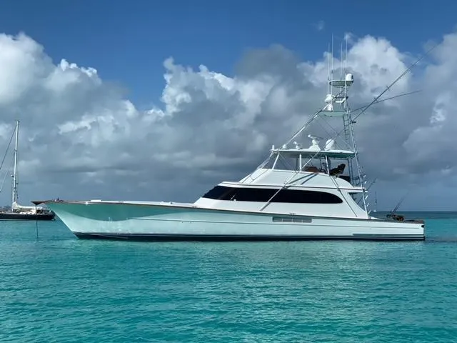 The Image of Merritt 80' Sportfish yacht, 2000 model, anchored in clear turquoise waters under a cloudy sky. - 0