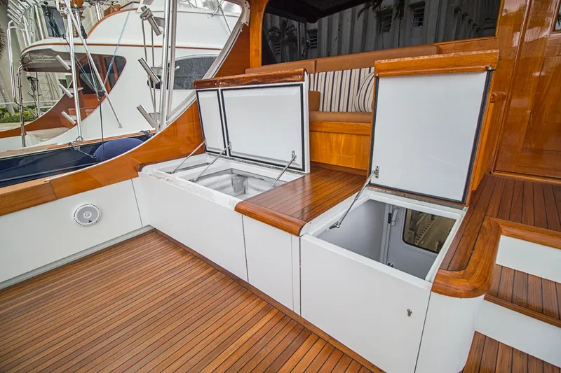 Slide: The Image of Luxury Merritt 80' Sportfish yacht deck with open storage compartments, showcasing elegant wood finish. - 13