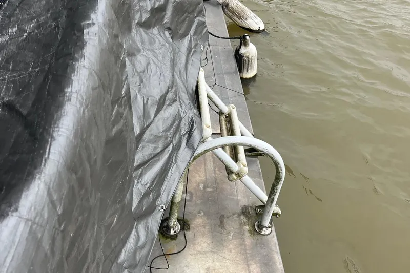 Slide: The Image of 1986 Waterhouse 14 X 44 houseboat with tarp and railing on a calm river. - 14