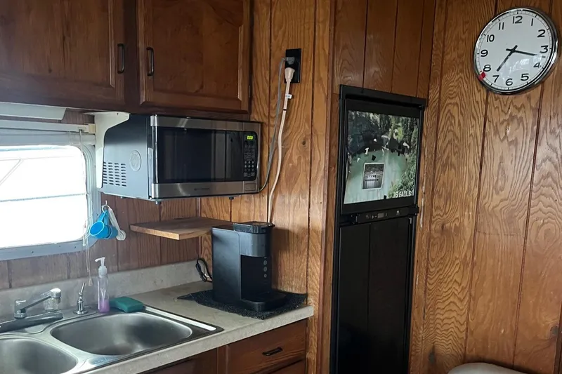 Slide: The Image of Interior of 1986 Waterhouse 14 X 44 houseboat kitchen with microwave, sink, and clock. - 6