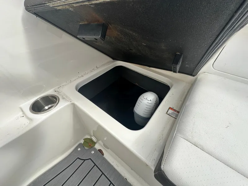 Slide: The Image of 2021 Sea Ray SPX 190 OB storage compartment with open lid and visible cup holder. - 14