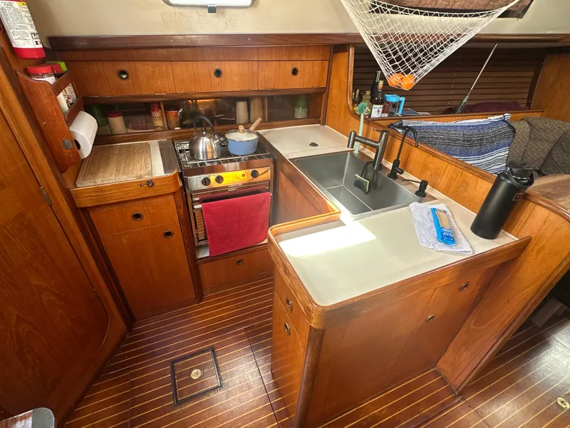 Slide: The Image of Interior of 1986 Beneteau First 375 sailboat kitchen with wooden cabinetry and modern appliances. - 13