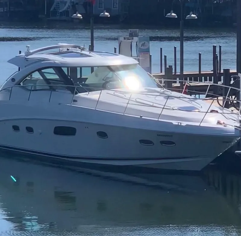 Slide: The Image of 2009 Sea Ray 470 Sundancer yacht docked at a marina, reflecting sunlight on water. - 2